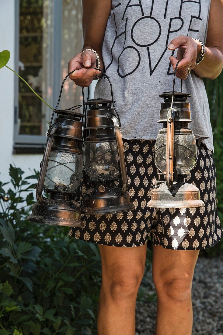 Woman carrying three vintage storm lamps