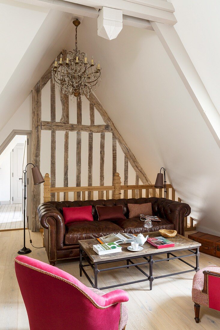 Loungebereich im Dachgeschoss mit pinkfarbenem Sessel und braunem Ledersofa