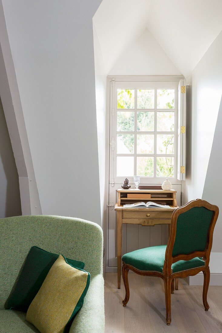 Schreibtischplatz mit antikem Polsterstuhl in Gaubennische vor Sprossenfenster