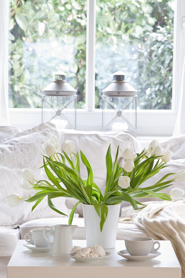 Weisser Tulpenstrauss auf Kaffeetisch vor gemütlicher Couch