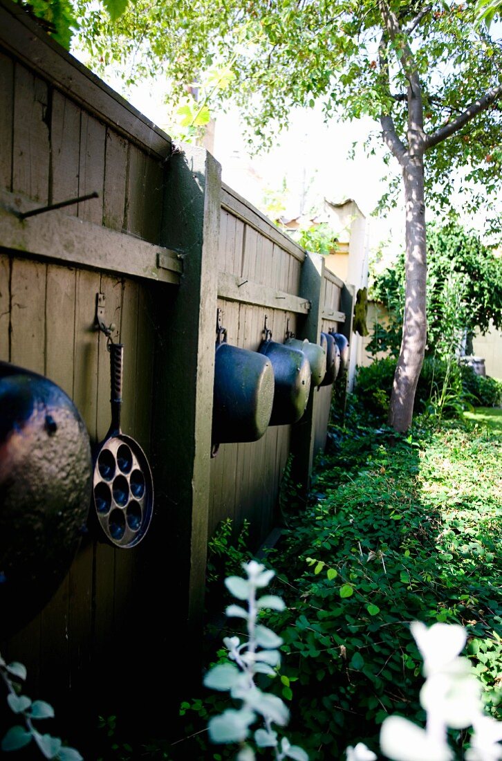 Old saucepans hung on garden fence