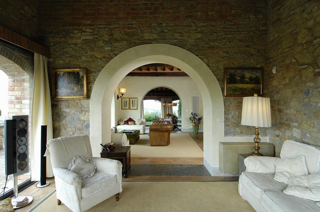 Mediterranes Wohnzimmer mit Natursteinwand und Rundbögen