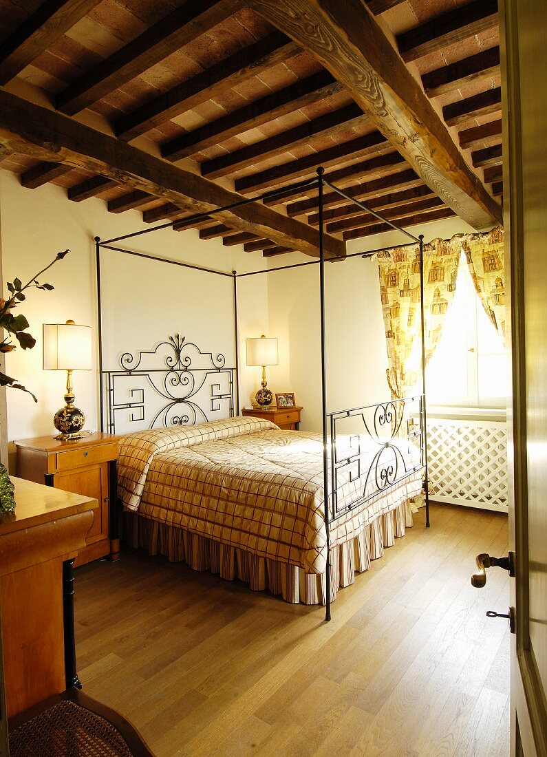 Four-poster bed in Mediterranean bedroom with wood-beamed ceiling