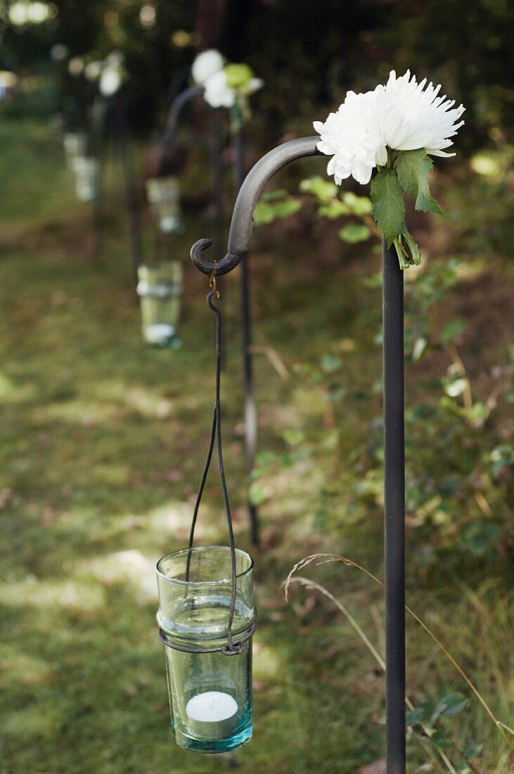 Row of wrought iron hooks decorated for wedding with flowers and candle lanterns