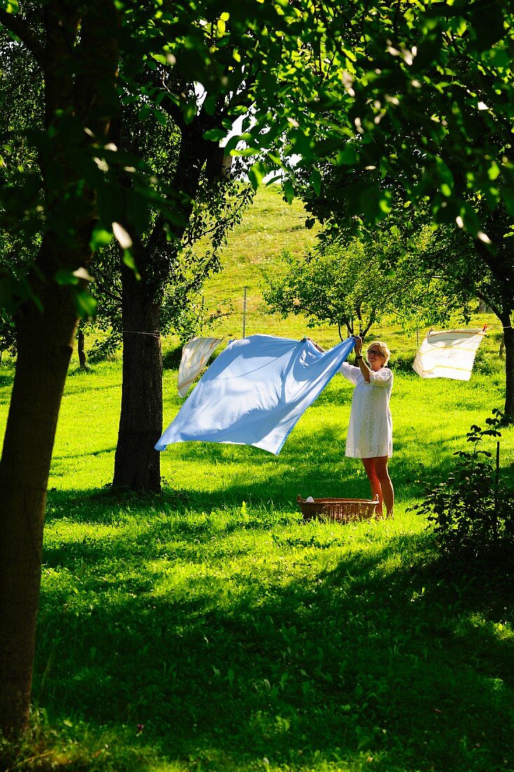Frau hängt Wäsche auf im Garten