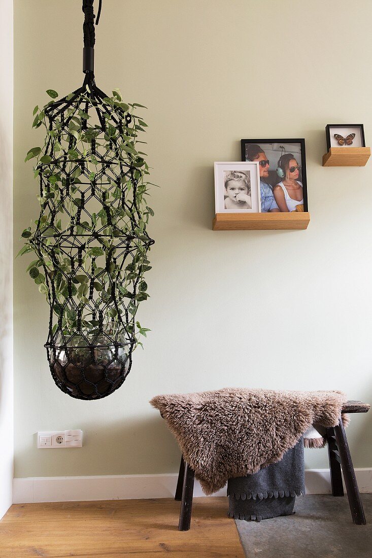 Large macrame plant next to stool covered in sheepskin blanket