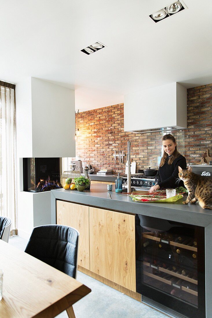 Frau und Katze in einer modernen Küche mit Backsteinwand