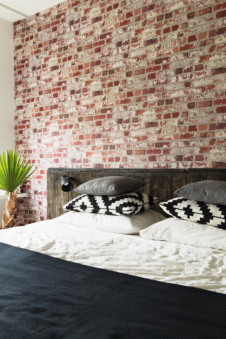 Schlafzimmer mit Backsteinwand und rustikalem Betthaupt