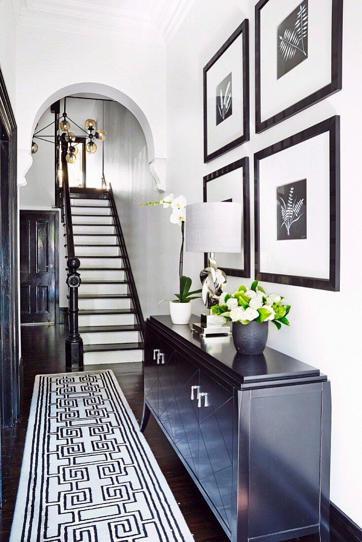 Schwarz-weißer Treppenaufgang in elegant renovierter Altbaudiele mit Rundbogen