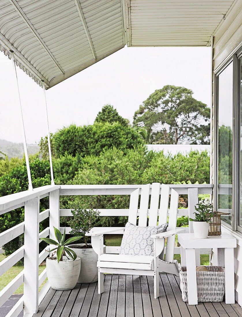 Covered terrace with white wooden armchair in country style; View over parapet railing to Gartn