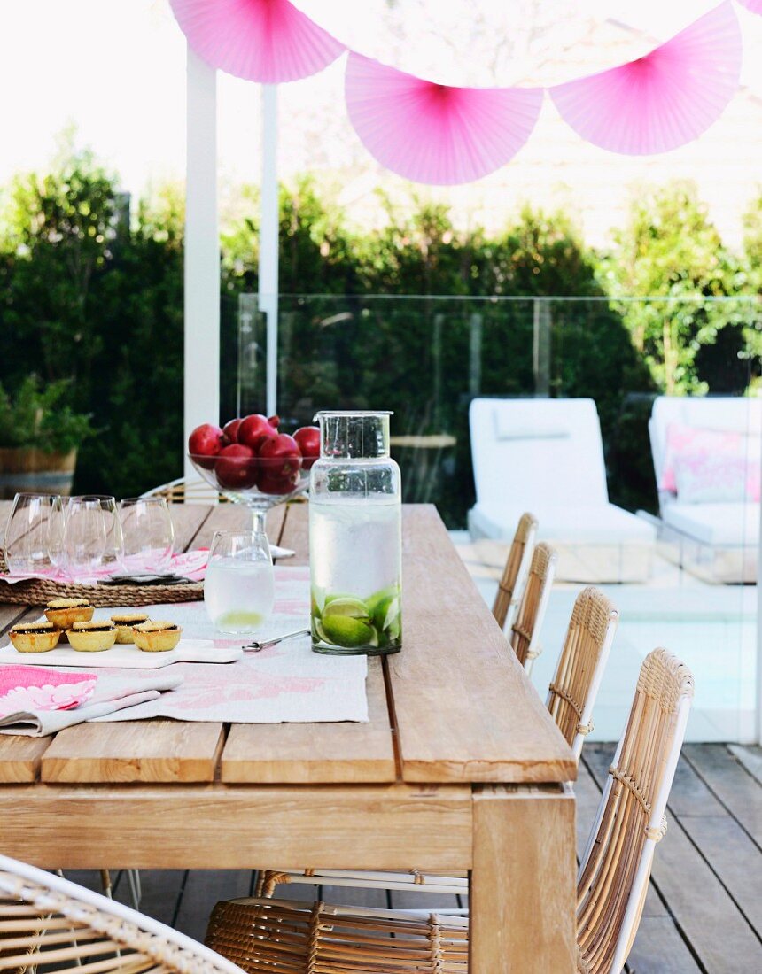 Rosafarbene Lampions auf sommerlicher Terrasse mit Holztisch