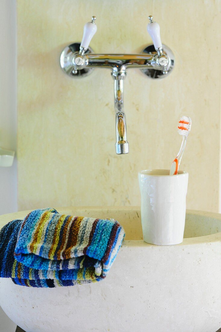 Toiletries on stone sink below vintage-style, wall-mounted taps