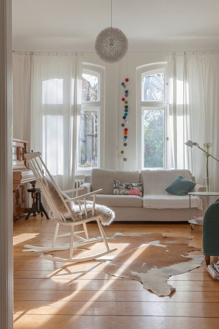 Wohnzimmer mit weißem Schaukelstuhl und Sofa am Fenster