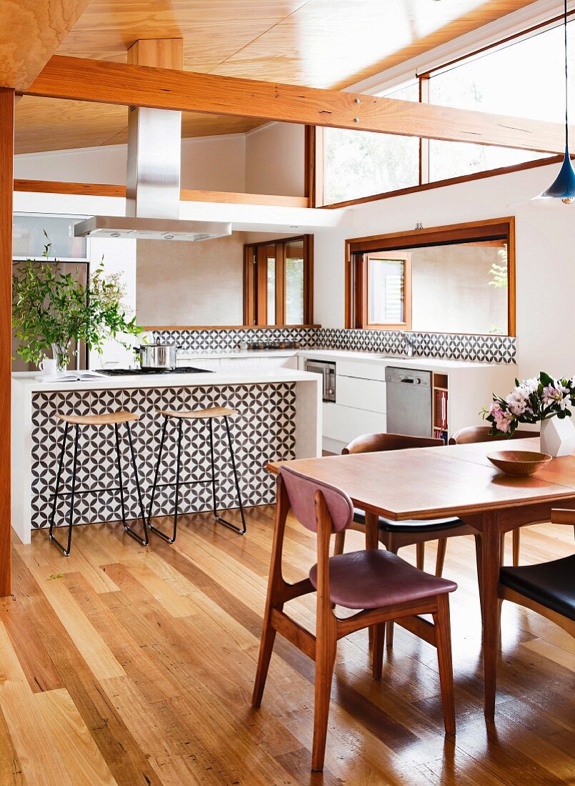 Dining area with classic chairs in front of an open kitchen with a free-standing counter and black and white tile pattern