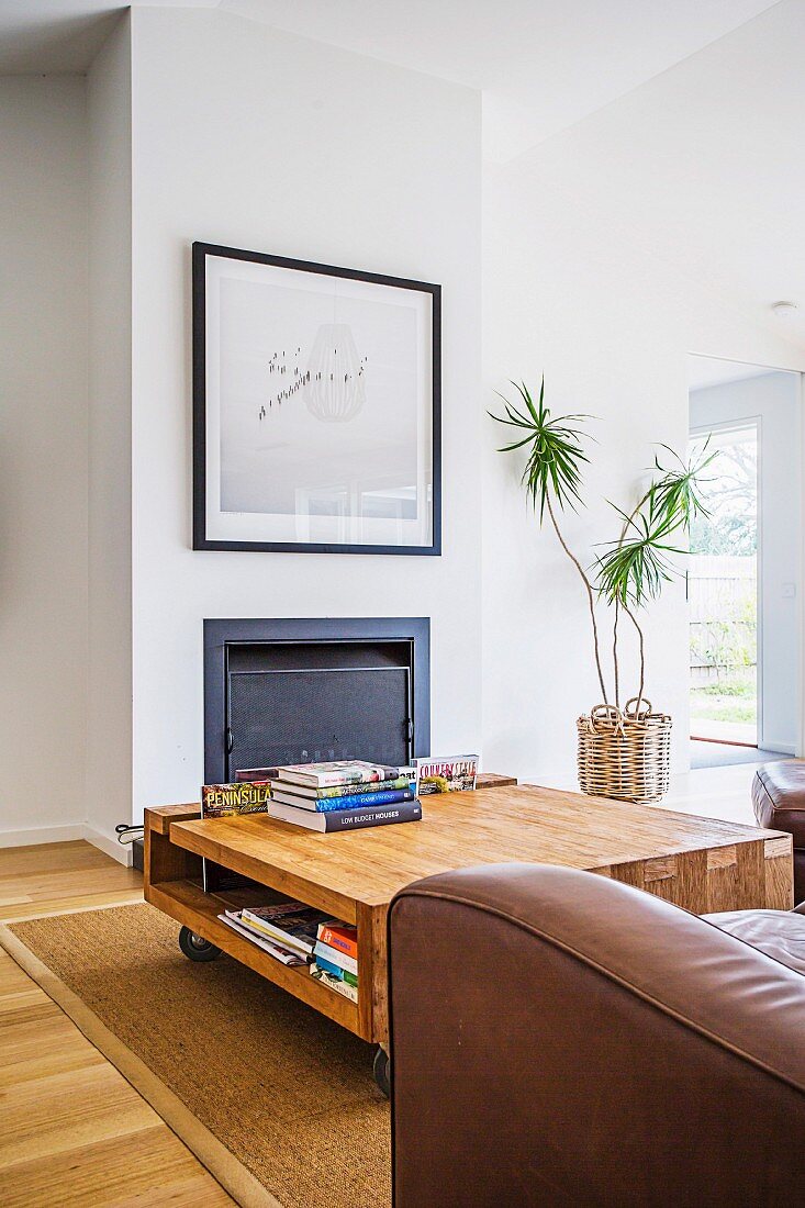 Solid coffee table on castors in front of a fireplace with a framed picture