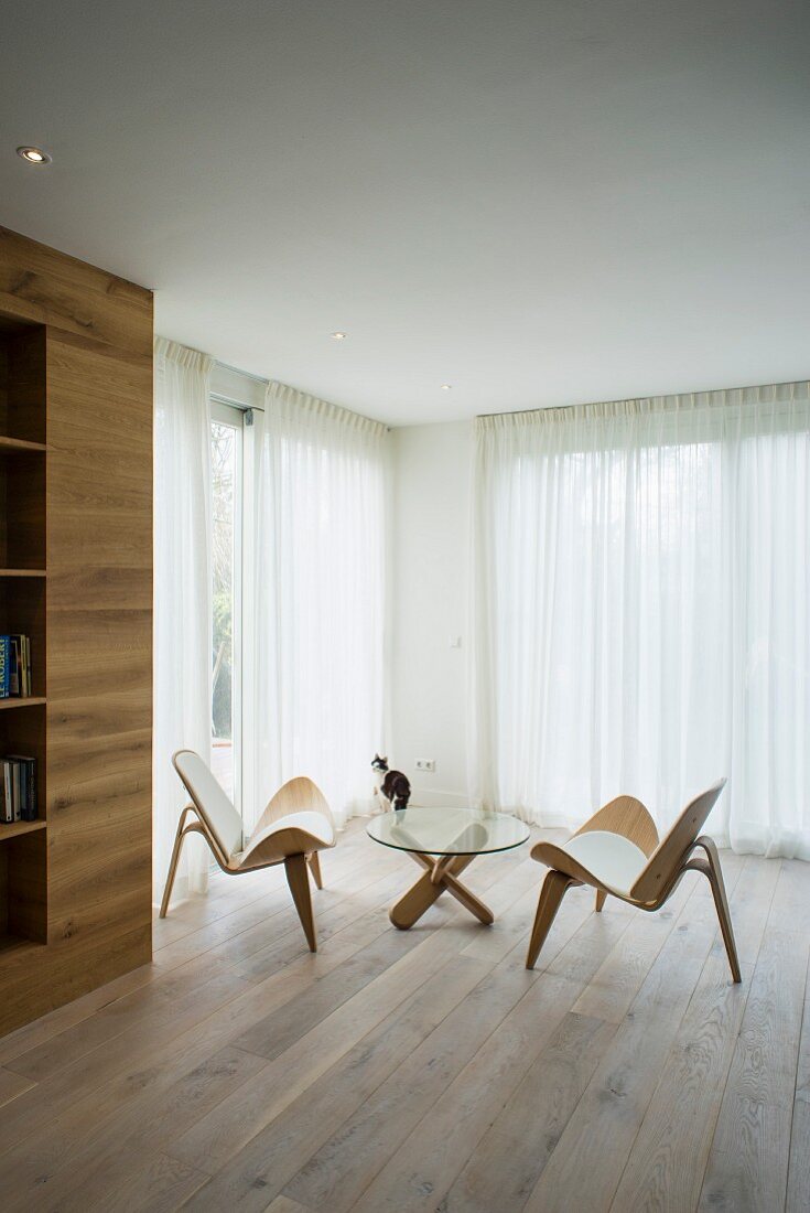 Minimalistisch möblierter Wohnraum mit Designermöbeln und Eichenboden