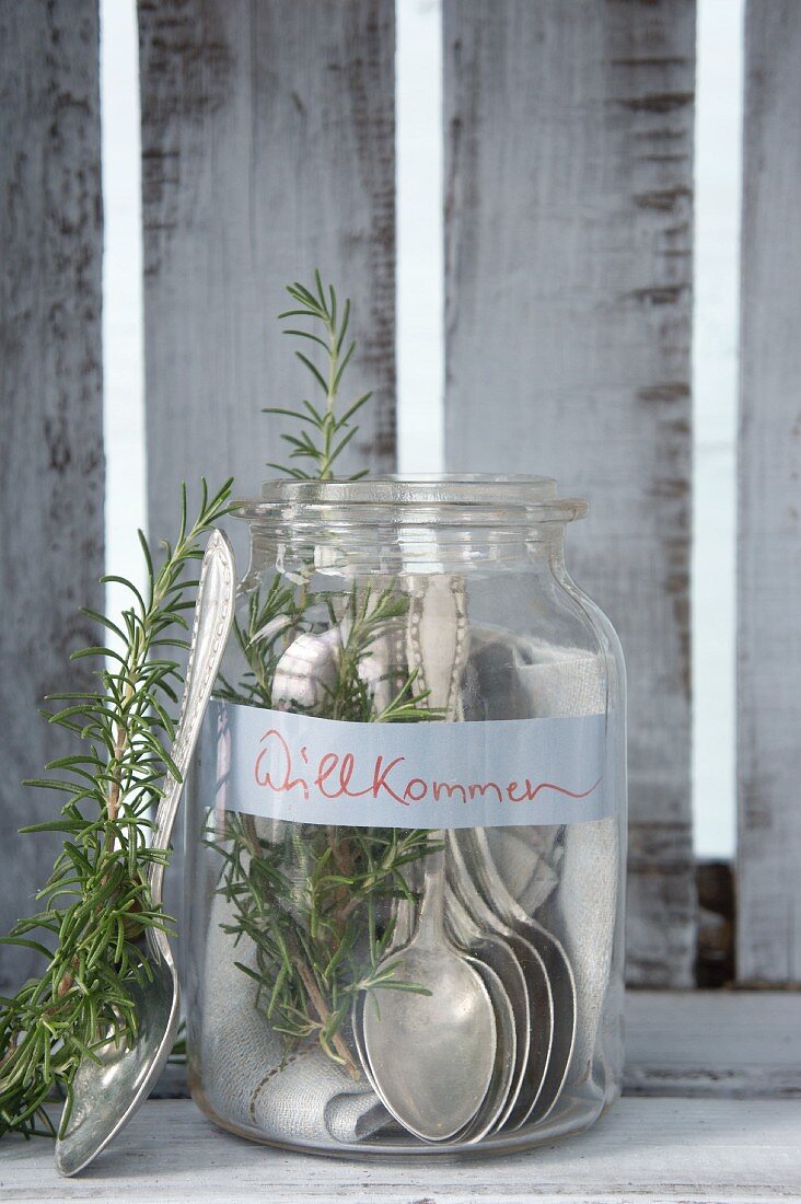 Silver spoons and rosemary in mason jar with welcome sign