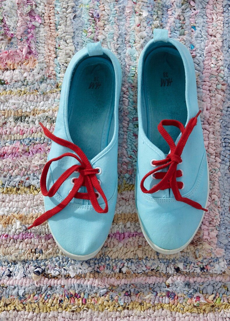 Hellblau gefärbte Sneakers mit roten Schnürsenkeln