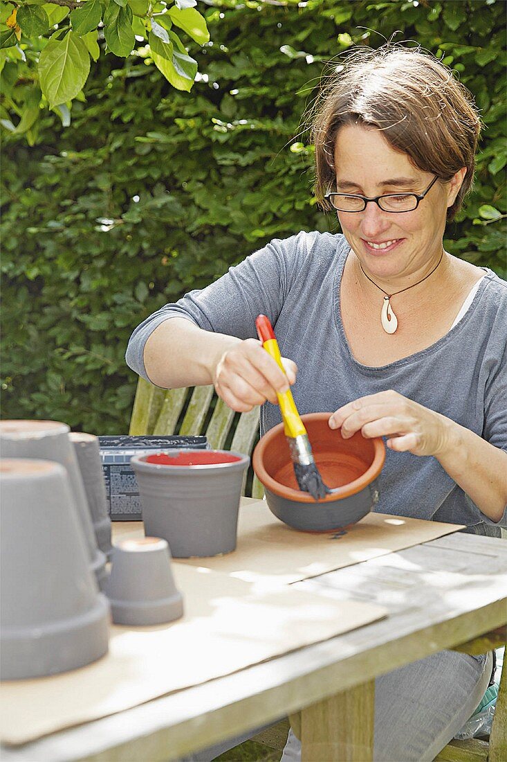 A woman painting flowerpots grey