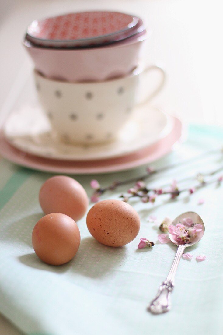 Eier und Blumen vor gestapelten Tassen