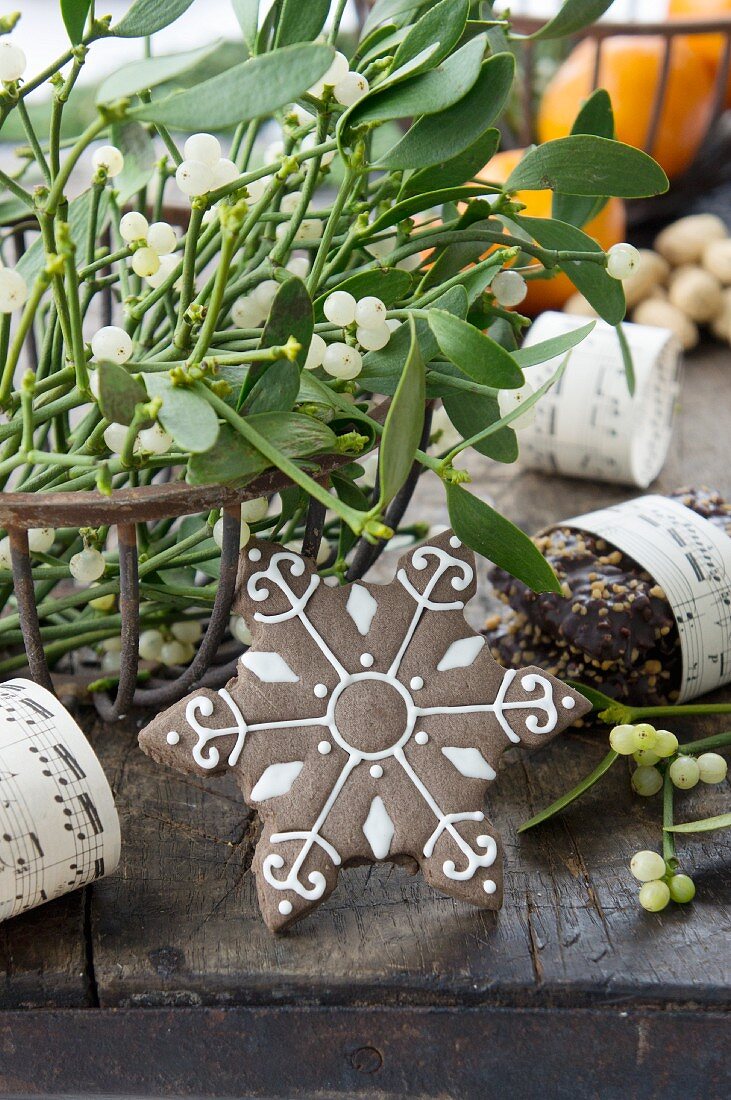 Metallkorb mit Mistelzweigen und einem Schneeflocken-Plätzchen (weihnachtlich)