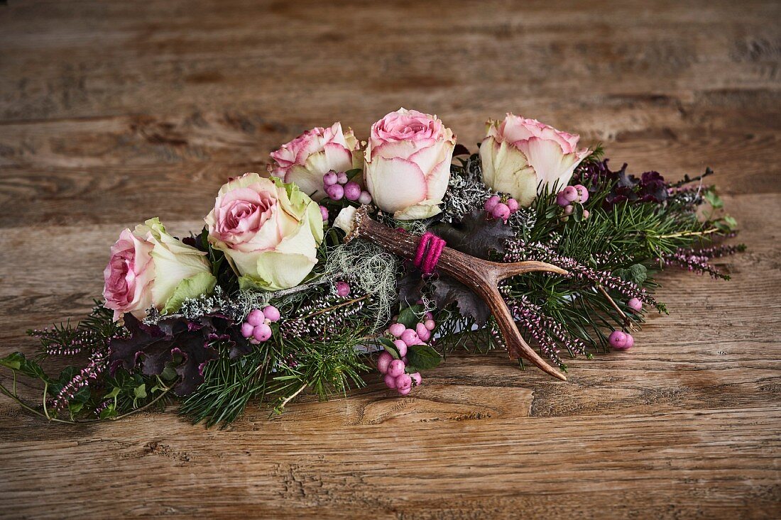 Alpine-style arrangement of roses, antlers, snowberries and heather