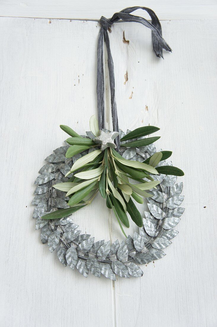Wreath of silver-grey metal leaves decorated with olive sprig