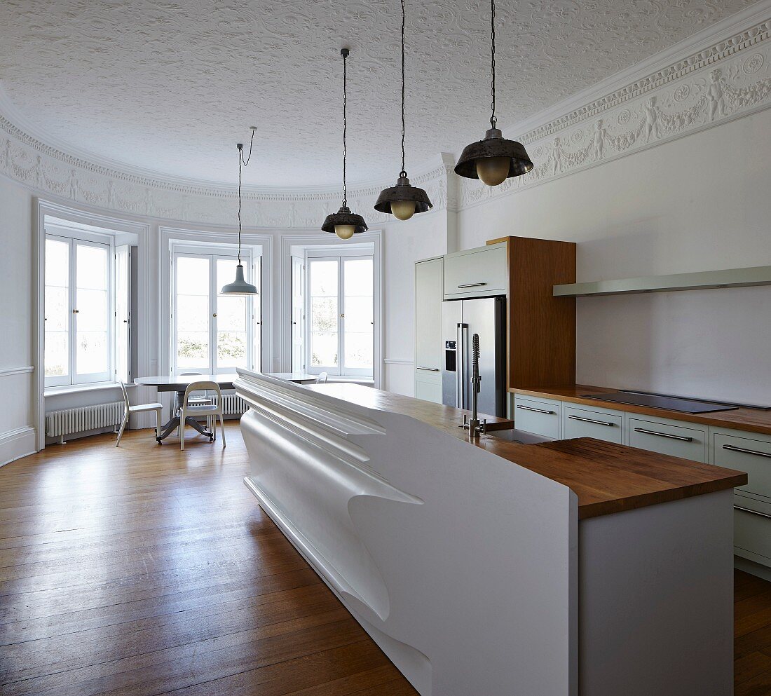 Minimalist, modern kitchen and artistically moulded half-height partition wall in period building with stucco frieze