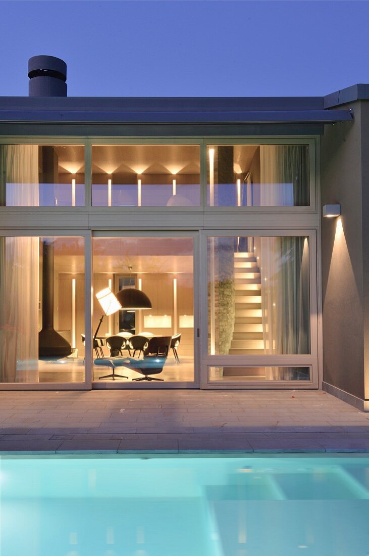 Pool outside contemporary house with illuminated interior