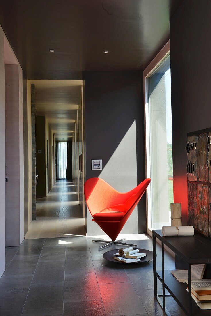 Classic red easy chair next to panoramic window in room painted dark grey