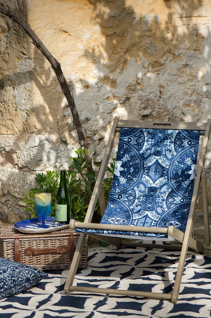 Sommerlicher Sitzplatz mit Liegestuhl und blauen Textilien