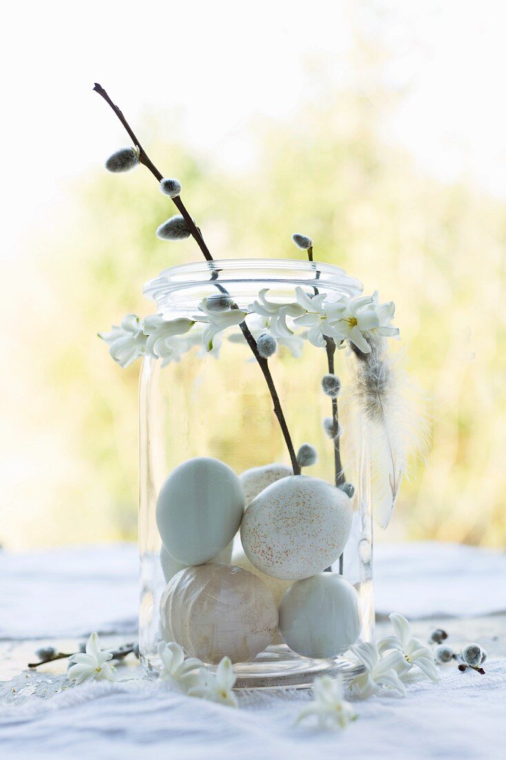 Pale eggs and pussy willow twigs in preserving jar with garland of hyacinth florets