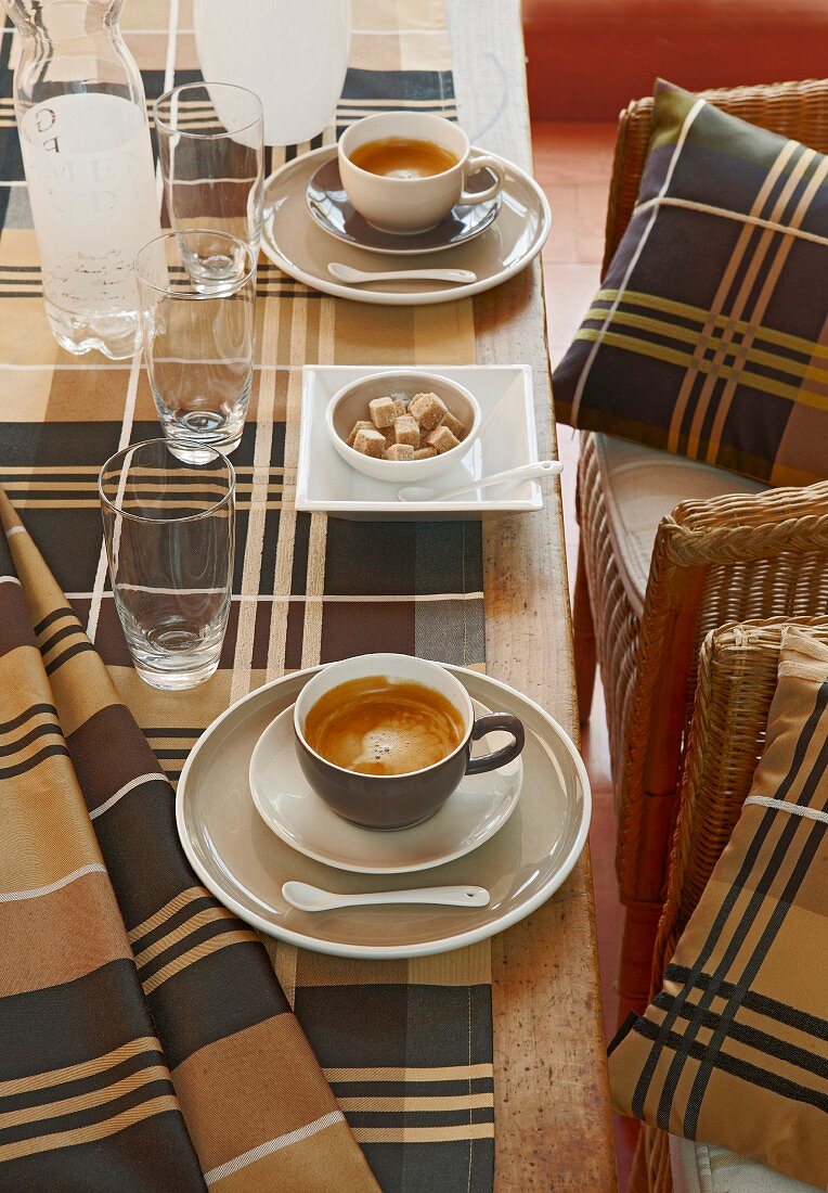 Kaffeetisch mit karierter Tischdecke und Stühlen mit passenden Dekokissen