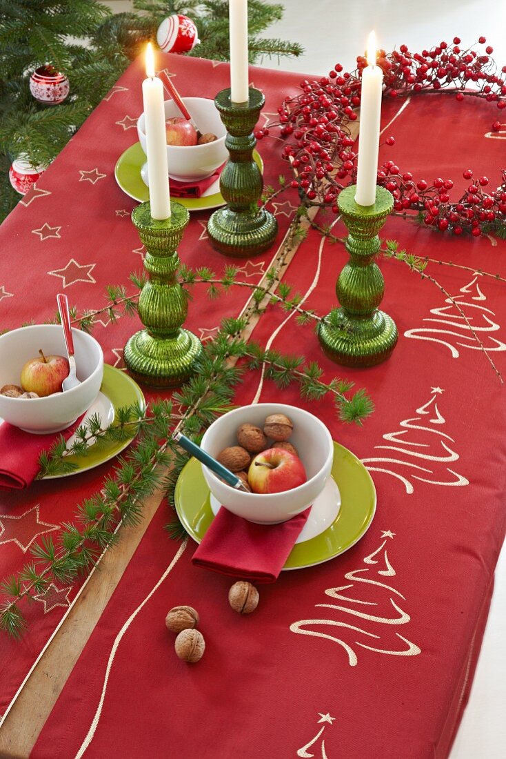 Table festively decorated in green and red with candlesticks and wreath of berries
