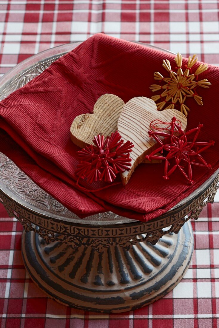Wooden hearts and straw stars on red linen cloth on decorative dish