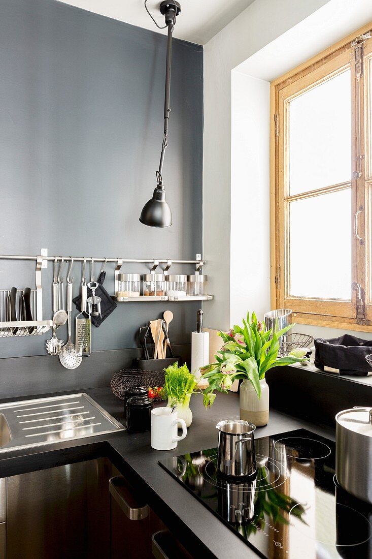 Dunkle Küche mit grauer Wand und Wandhalterung für Utensilien