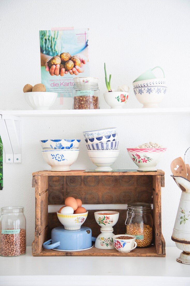 Vintage-style bowls on kitchen shelf and wooden crate