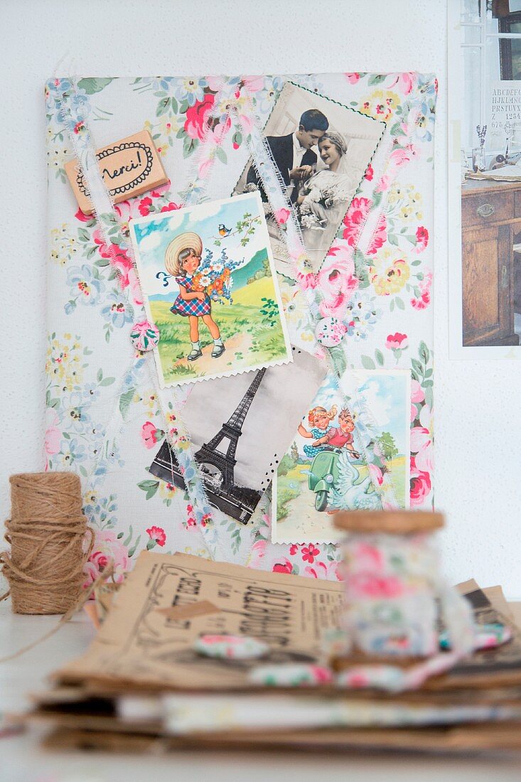 Vintage-style clippings from French magazines on floral fabric pinboard