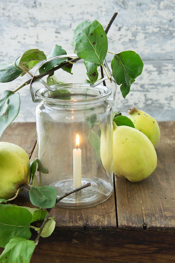 Candle in mason jar with clip on rim and quinces on table