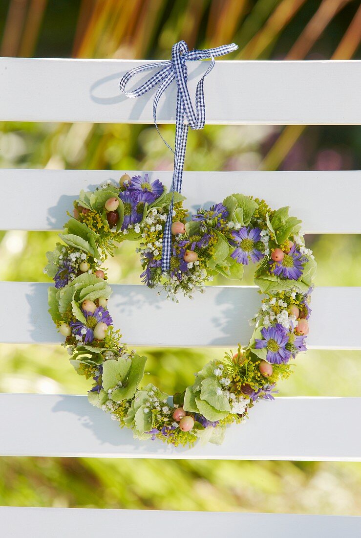 Heart-shaped wreath of flowers hung on bench backrest