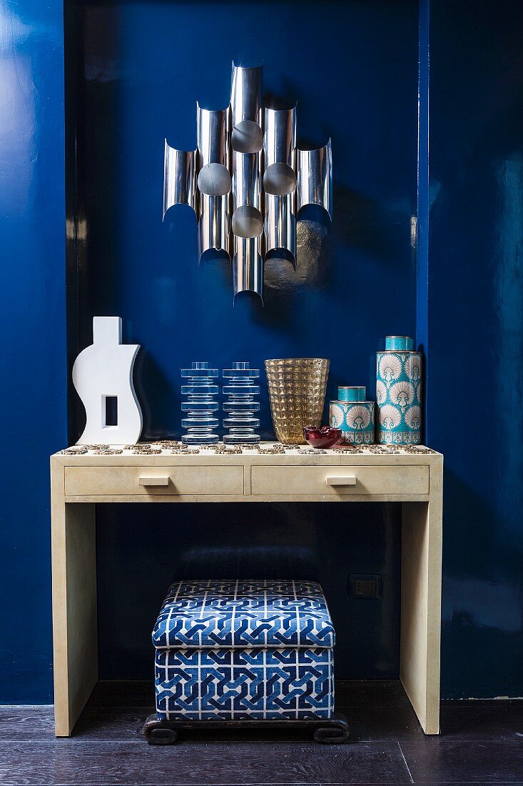 Collection of vases on console table against royal-blue wall
