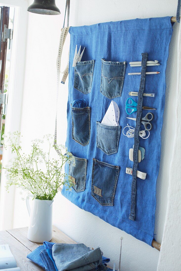 Sewing utensils in wall-mounted organiser made from old jeans pockets