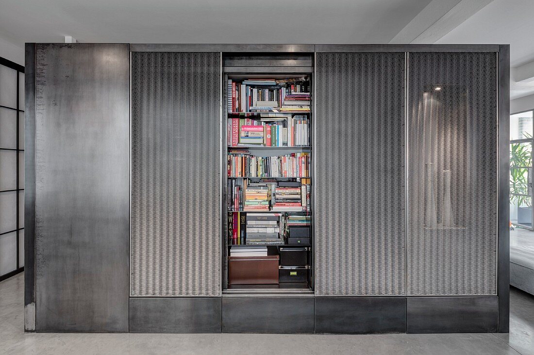 Grauer Kubus im Wohnraum mit verstecktem Bücherregal