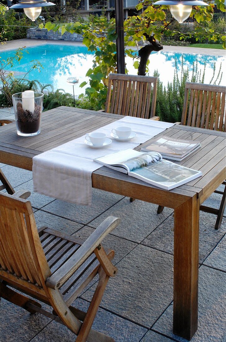 Holztisch mit Stühlen auf Terrasse am Pool