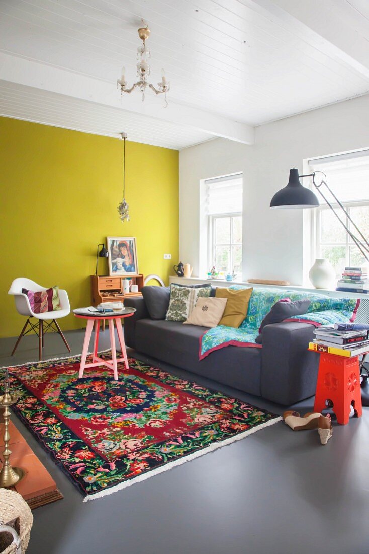 Farbenfrohes Wohnzimmer mit gelber Wand und buntem Teppich