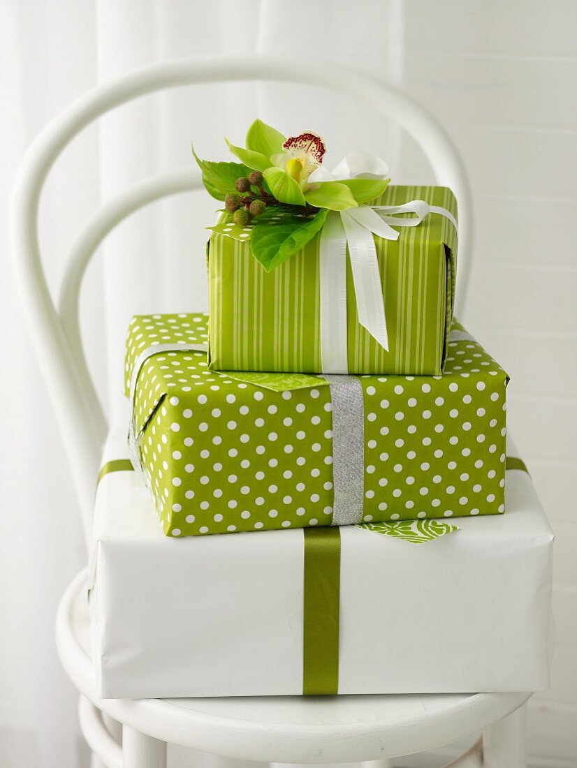 Gestapelte Geschenke in Grün und Weiß mit Blumendekoration