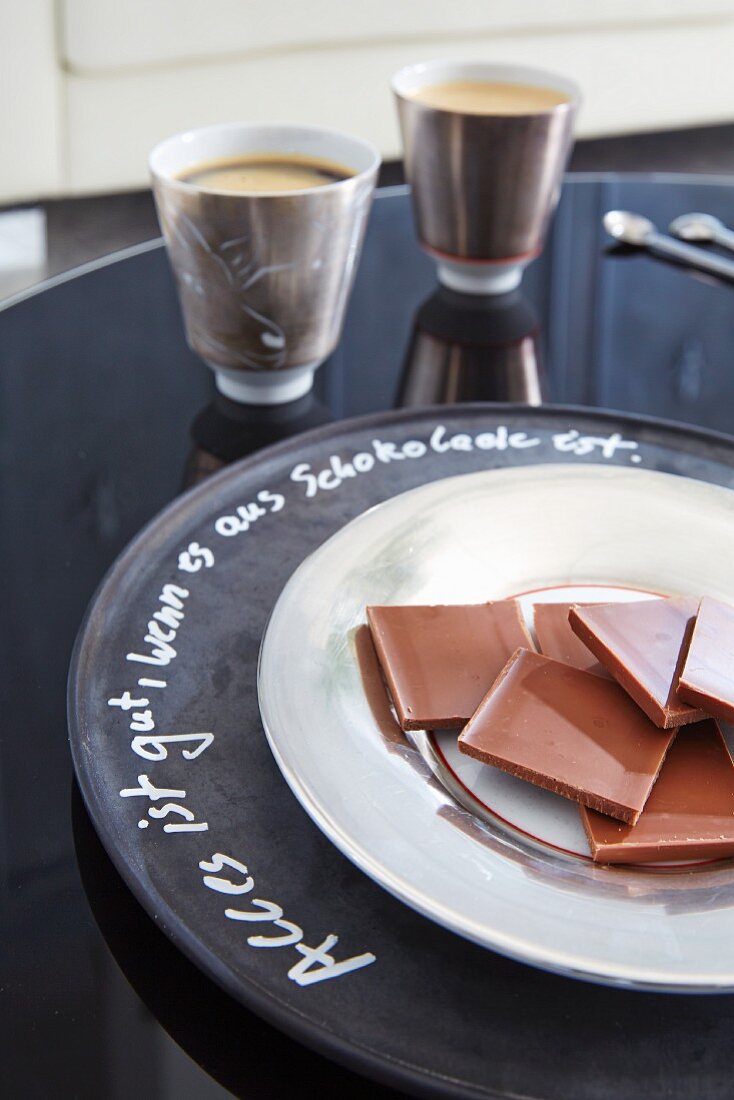 Squares of chocolate on plate on chalkboard charger plate with writing around rim