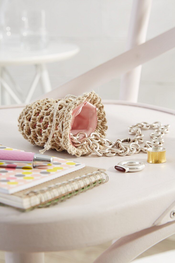 Jewellery spilling out of small, hand-crocheted bag lined in pink