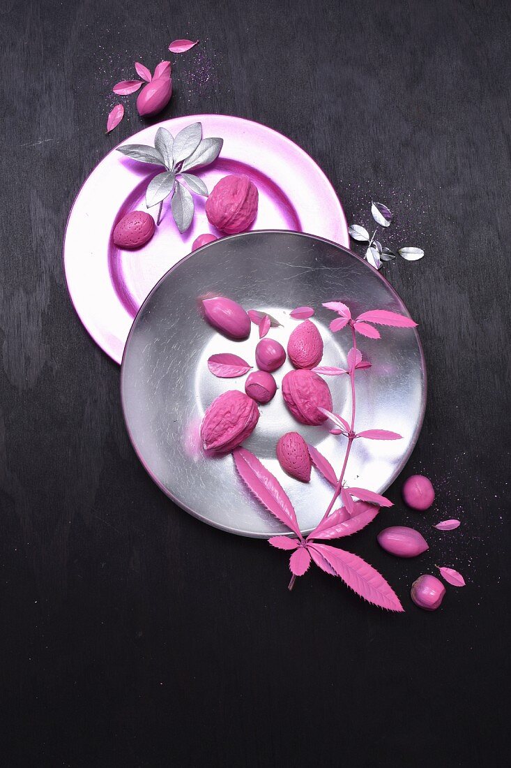 Tellerdeko aus pinkfarbenen Nüssen und Blättern
