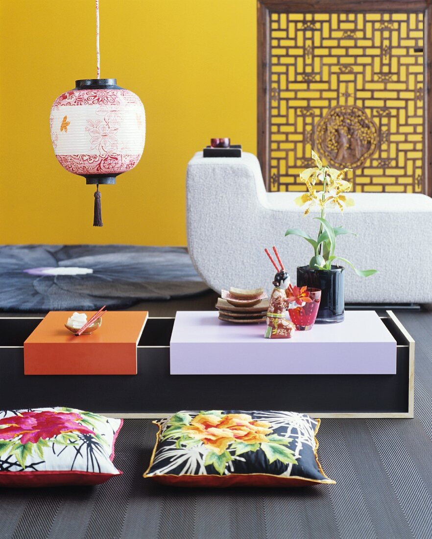 Niedriger Asia-Tisch mit Bodenkissen vor Polstermöbel und gelber Wand